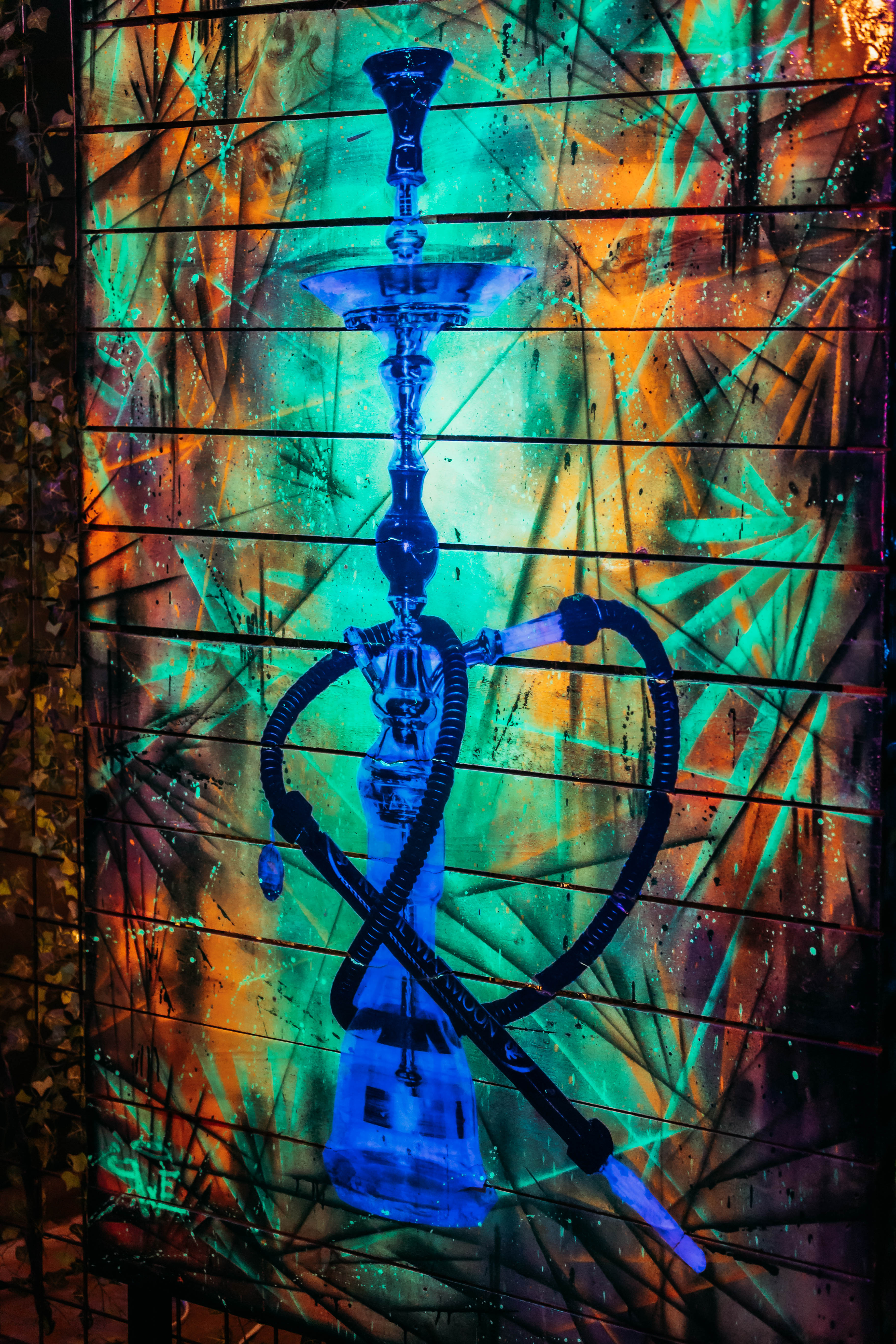 Glowing hookah against vibrant wall art inside Hookava